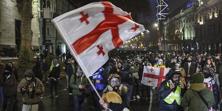 epa11761270 A supporter of the Georgian opposition holds a Georgian flag during a protest in front of the Parliament building in Tbilisi, Georgia, 06 December 2024. Thousands of pro-EU activists continue their protests in the Georgian capital against the country's ruling party decision to suspend accession talks with the European Union (EU) until the end of 2028.  EPA-EFE/DAVID MDZINARISHVILI
