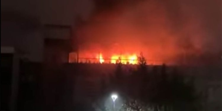 Masked medical nurse holding syringe and doing injection of vaccine to elderly woman at home