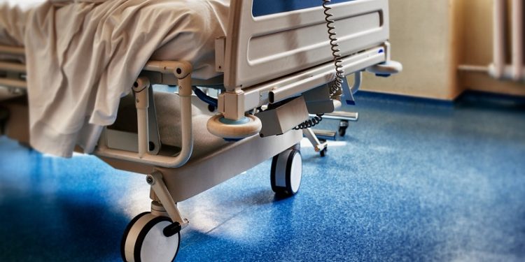 Empty modern hospital bed in a sunny room with a clean blue floor